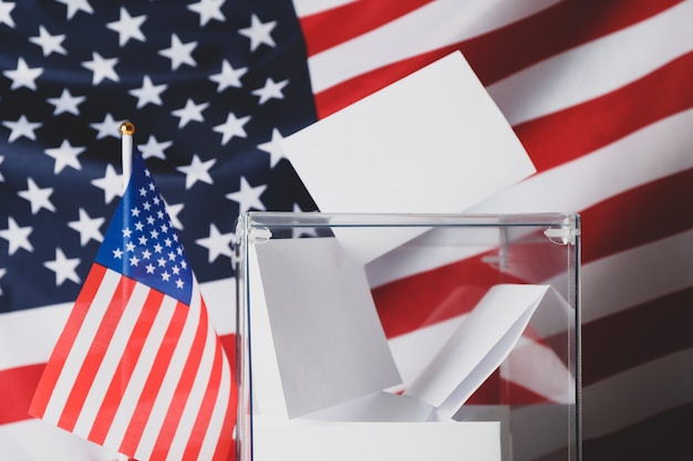 Photo boîte de vote avec des bulletins sur le drapeau américain