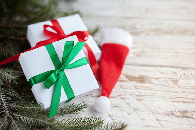 Boîtes blanches de Noël ou cadeaux avec Bonnet de Noel sur une table en bois blanche.