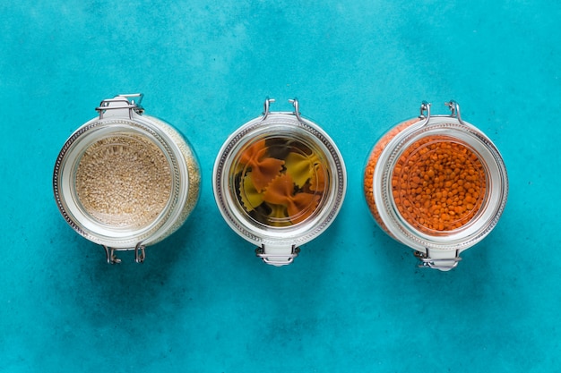 Boîtes et bouteilles en verre avec quinoa, lentilles, pâtes organisées à la maison