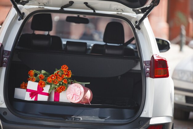 Boîtes, cadeaux, cadeaux et fleurs dans le porte-bagages ou le coffre à bagages de la voiture. Toujours d'automabile avec des tulipes et des cadeaux au jour de la femme.