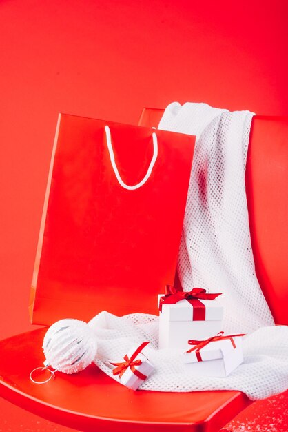 Photo boîtes de cadeaux de noël et décorations de fête sur écharpe blanche sur le paquet de papier rouge de la chaise rouge