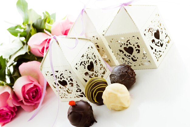 Boîtes carrées décoratives en forme de coeur en dentelle blanche remplies de truffes gourmandes.