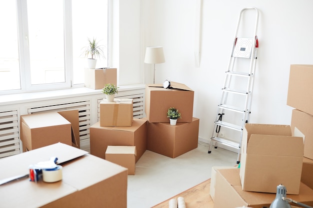 Boîtes en carton empilées dans une salle blanche vide, déménagement, déménagement et concept de décoration de maison