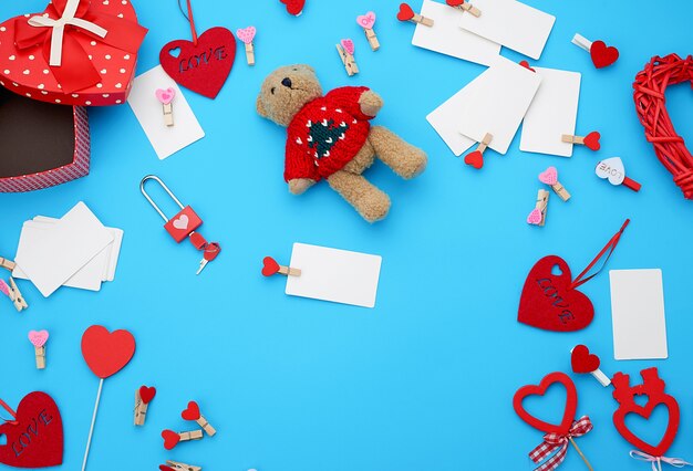 Boîtes en carton en forme de coeur, un petit ours en peluche, des cartes de visite vierges blanches avec des pinces à linge sur fond bleu