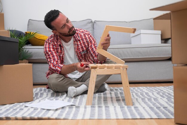 Photo boîtes en carton jeune homme engage l'assemblage d'étagères diy dans sa nouvelle maison après le déménagement