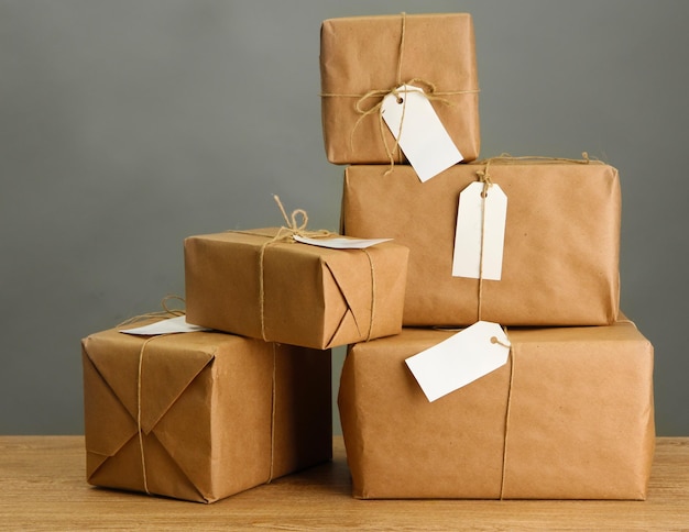 Boîtes de colis avec papier kraft sur table en bois sur fond gris