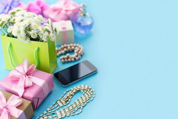 Boîtes de composition décorative avec des bijoux de cadeaux fleurs femmes shopping vacances fond bleu