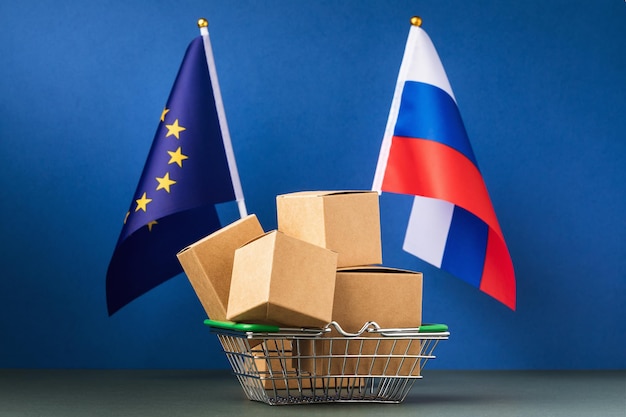 Boîtes dans un panier alimentaire et deux drapeaux le concept de commerce entre l'Union européenne et la Russie