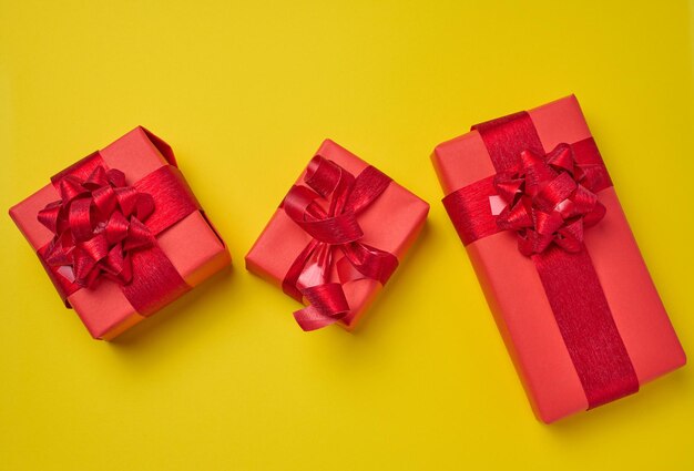 Boîtes emballées dans du papier rouge et attachées avec un ruban sur un fond jaune cadeaux