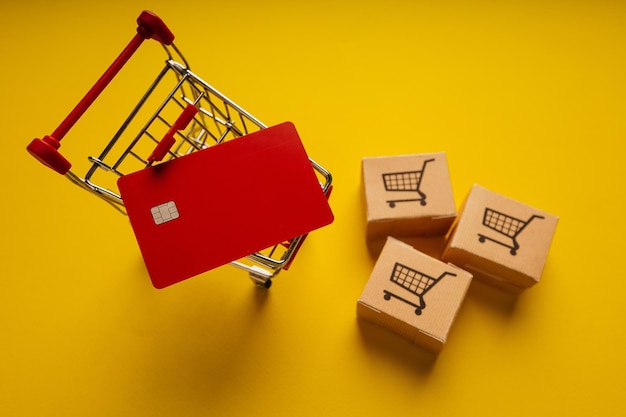 Boîtes de livraison de panier et carte de crédit rouge sur fond jaune