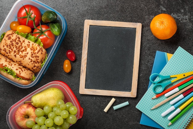 Boîtes à lunch et fournitures scolaires sur noir