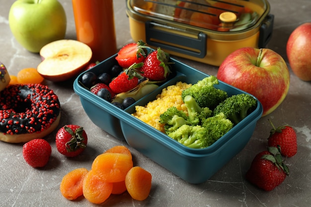 Boîtes à lunch avec de la nourriture savoureuse sur une table texturée grise