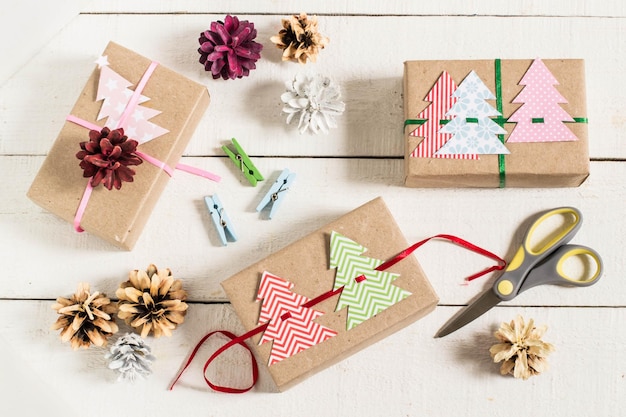 Les boîtes sont emballées dans du papier kraft, attachées avec des rubans avec des arbres de Noël colorés faits maison