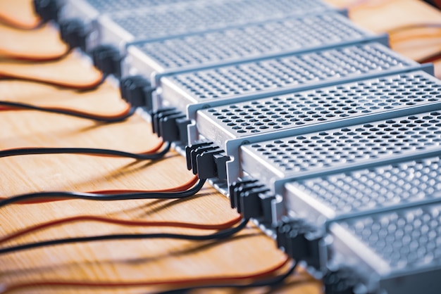 Les boîtiers d'alimentation et de fils en maille métallique sont sur une table en bois lors de la production d'ordinateurs de haute technologie. Concept de haute technologie et production industrielle