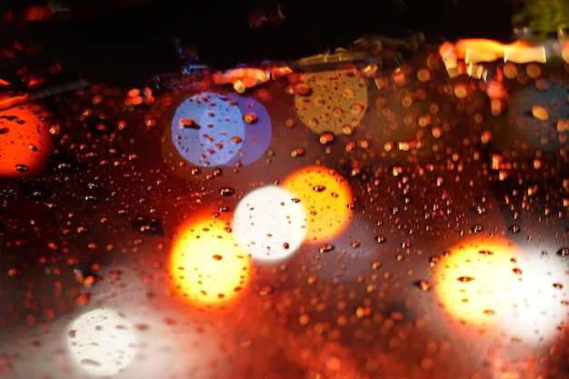 Bokeh coloré des phares du véhicule sur verre le jour de pluie la nuit.