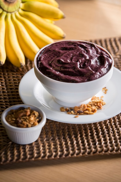 Photo bol açai avec bananes et granola sur surface rustique