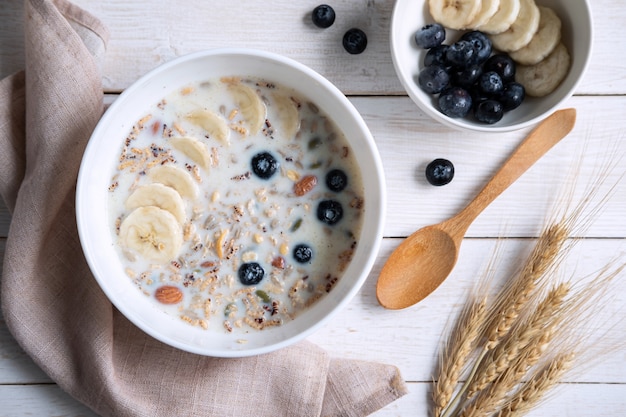 Bol d'amandes granola et céréales avec myrtille et banane sur table en bois, petit-déjeuner sain