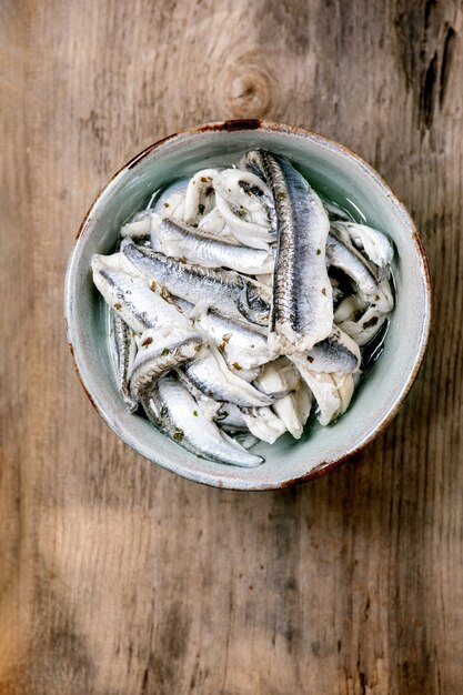 Bol d'anchois marinés ou filet de sardines à l'huile aux herbes pour tapas ou antipasti sur vieux bois