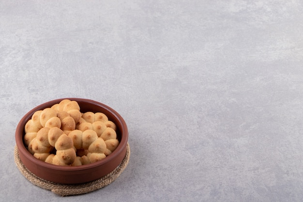 Bol d'argile de biscuits sucrés en forme de fleur sur table en pierre.