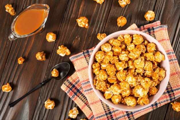 Bol en argile avec pop-corn au caramel sur fond plat en bois