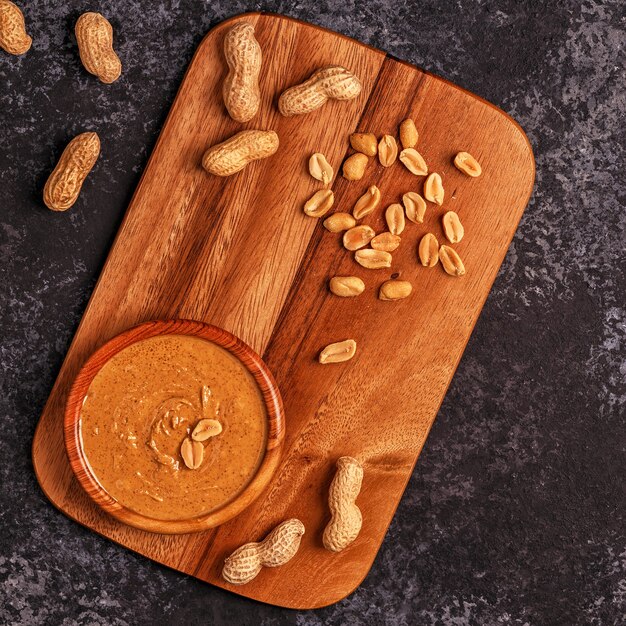 Bol de beurre d'arachide sur planche de petit-déjeuner en bois