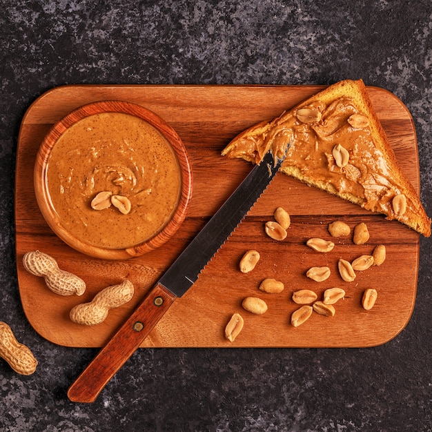 Bol de beurre d'arachide sur planche de petit-déjeuner en bois