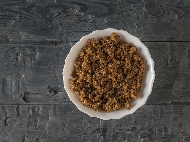 Bol blanc de bouillie de quinoa sur une table en bois. Mise à plat. Régime équilibré.