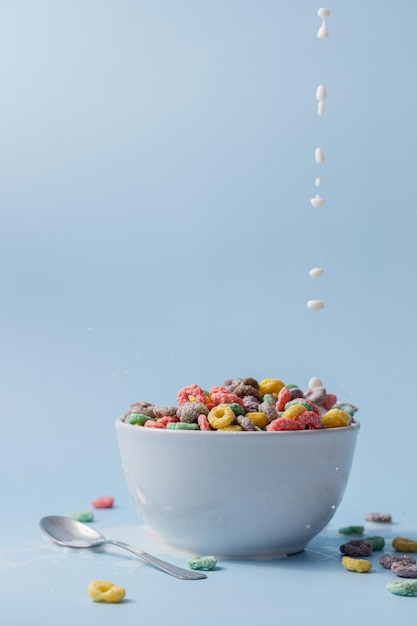 Photo un bol blanc avec des céréales et du lait en forme d'anneau coloré céréales et lait versés dans le bol