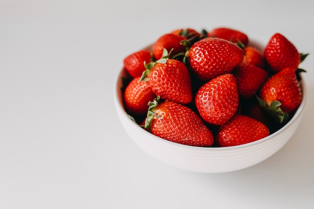 Bol blanc de fraises fraîches biologiques sur table