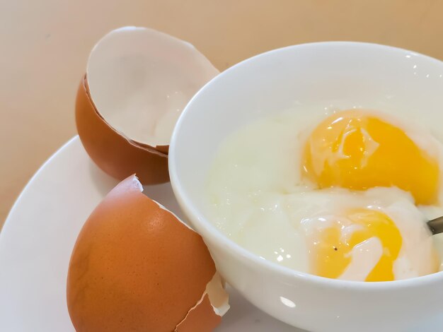 Bol blanc avec des œufs à moitié bouillis sur la table. Petit-déjeuner populaire malaisien.