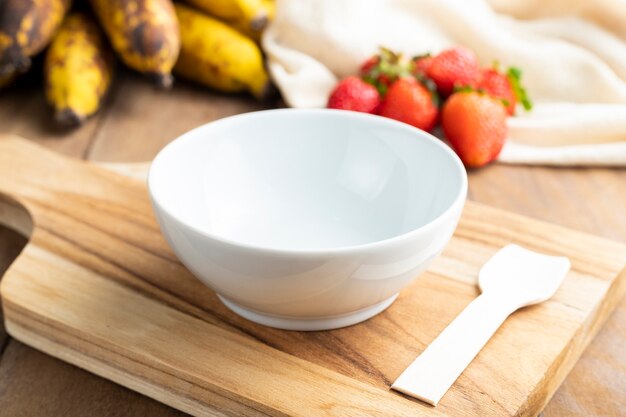 Bol blanc vide avec des fruits sur une table en bois