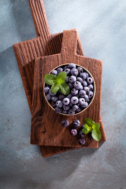 Bol de bleuets frais sur planche de bois rustique. Myrtilles d'aliments biologiques et feuille de menthe pour un mode de vie sain.