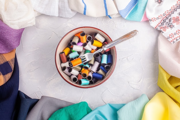 Bol avec bobines de fil et fourche dans un cadre en tissu multicolore