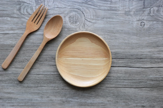 Bol en bois avec cuillère et fourchette sur fond de bois