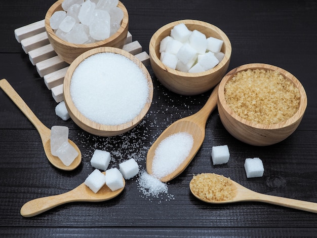 Bol en bois et une cuillère avec un morceau de sucre sur fond de bois foncé.