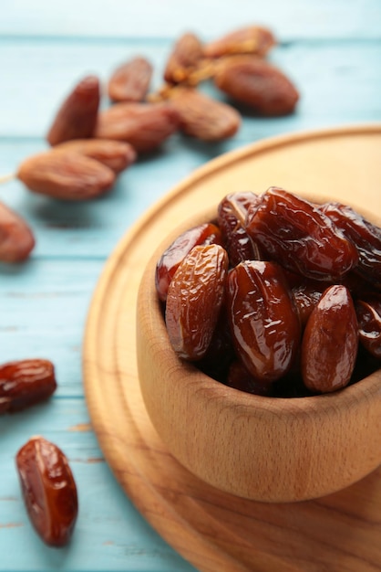 Bol en bois de dattes séchées sur fond de bois bleu. Branche avec dates sur bleu.