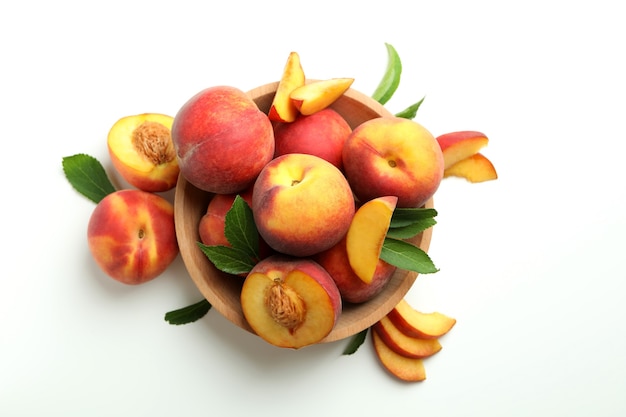 Bol en bois avec des fruits de pêche sur fond blanc