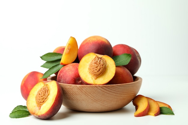 Bol en bois avec des fruits de pêche sur une table blanche