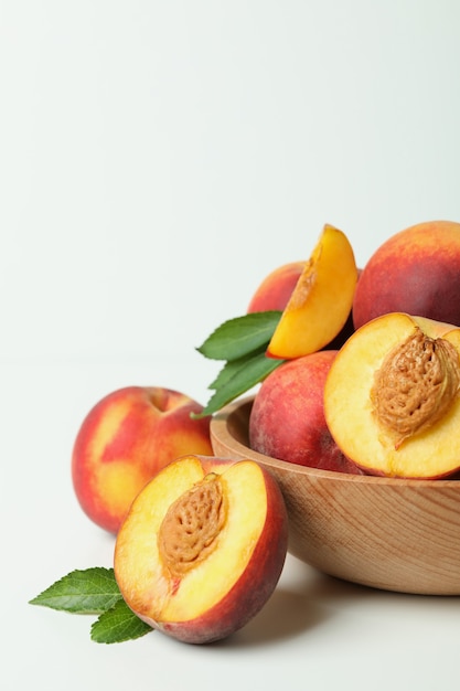 Bol en bois avec des fruits de pêche sur une table blanche