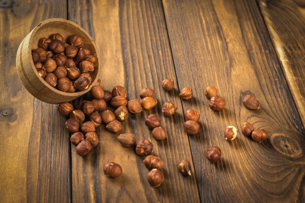 Un bol en bois inversé et des noisettes sur un fond en bois