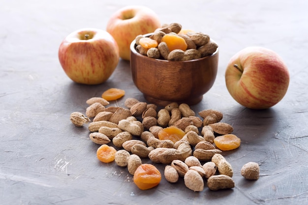 Bol en bois avec noix non pelées et fruits secs Pommes Fruits secs Cacahuètes Amande allongé sur fond