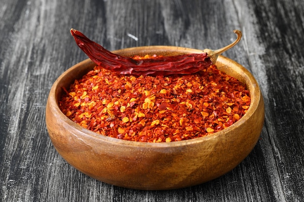 Bol en bois avec piment broyé et piment rouge frais sur l'ancienne table Mise au point sélective