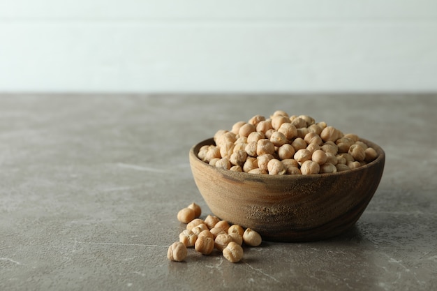 Bol en bois avec des pois chiches frais sur table grise