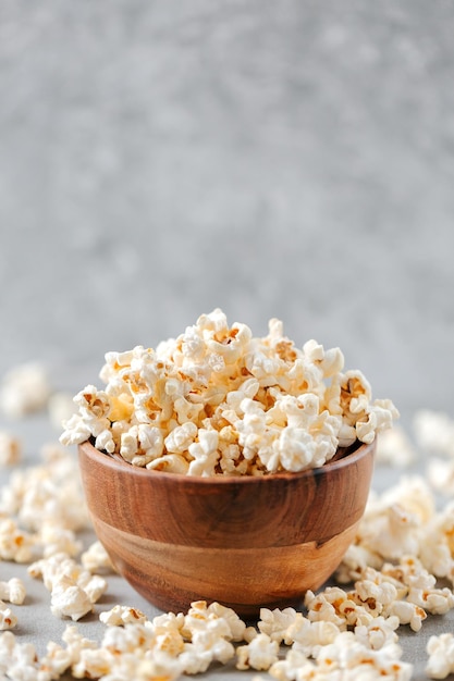 Un bol en bois de pop-corn salé sur une table grise rustique avec mise au point sélective et espace de copie