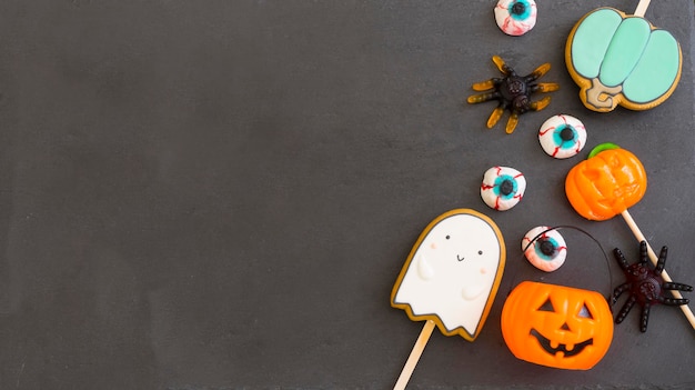 Bol de bonbons à la citrouille et différentes friandises pour halloween sur fond sombre