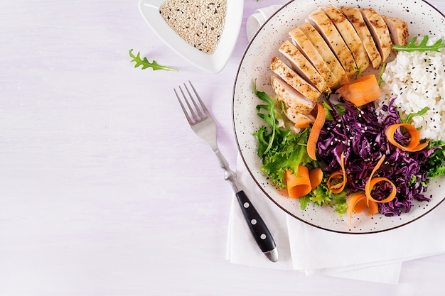 Photo bol à bouddha avec filet de poulet, riz, chou rouge, carotte, salade de laitue fraîche et sésame.