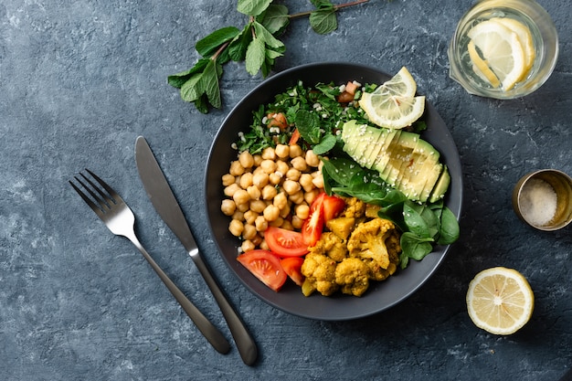 Bol de Bouddha Nourriture végétarienne équilibrée Aloo gobi, pois chiches, tomate, avocat, salade de tabule aux épinards