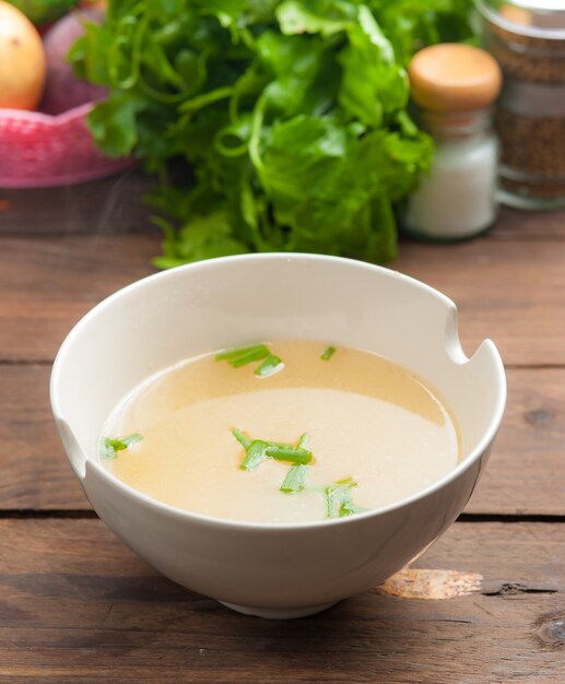 bol de bouillon et légumes frais sur bois