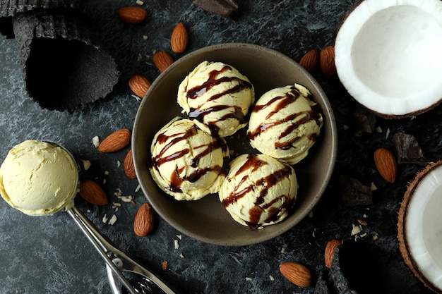 Bol avec des boules de crème glacée et des ingrédients sur table noire smokey