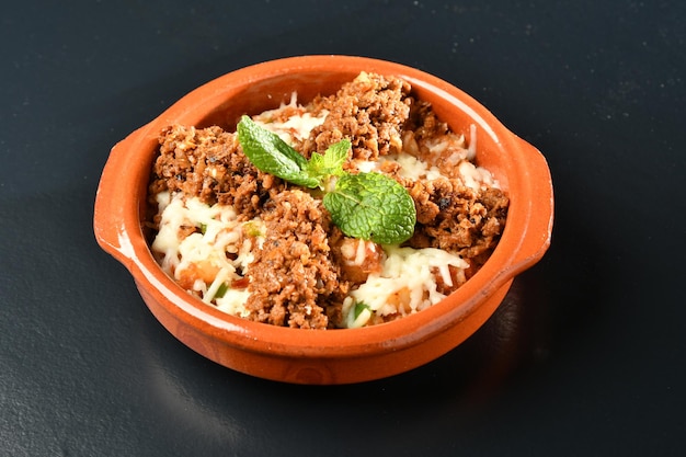 Un bol de casserole de boeuf haché avec un brin de basilic sur le dessus.